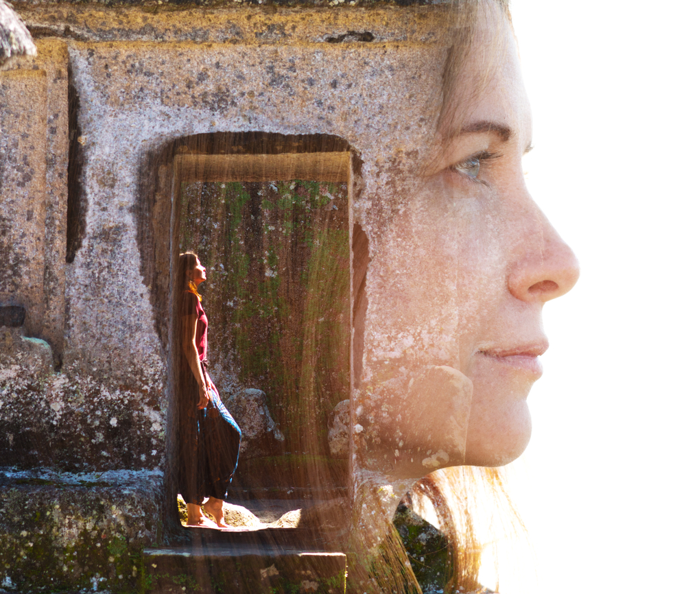 Double exposure portrait of a serene woman combined with a photograph of a traveller standing in a doorway of a temple in southeast asia