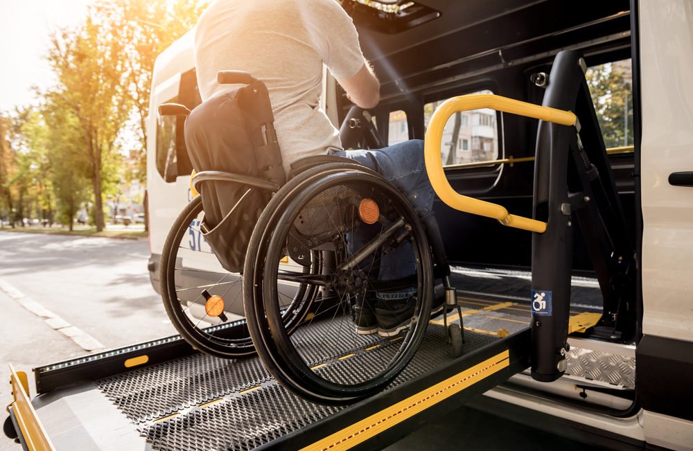 A man in a wheelchair on a lift of a vehicle for people with disabilities