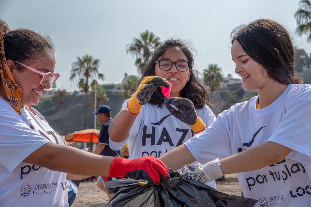 A woman holds up a condom found while volunteering to pick up tash at Agua Dulce beach for the 'Hazlo por tu Playa' campaign.