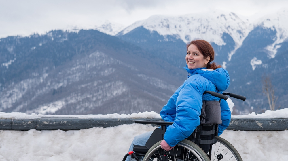 Caucasian woman in a wheelchair travels in the mountains in winter.