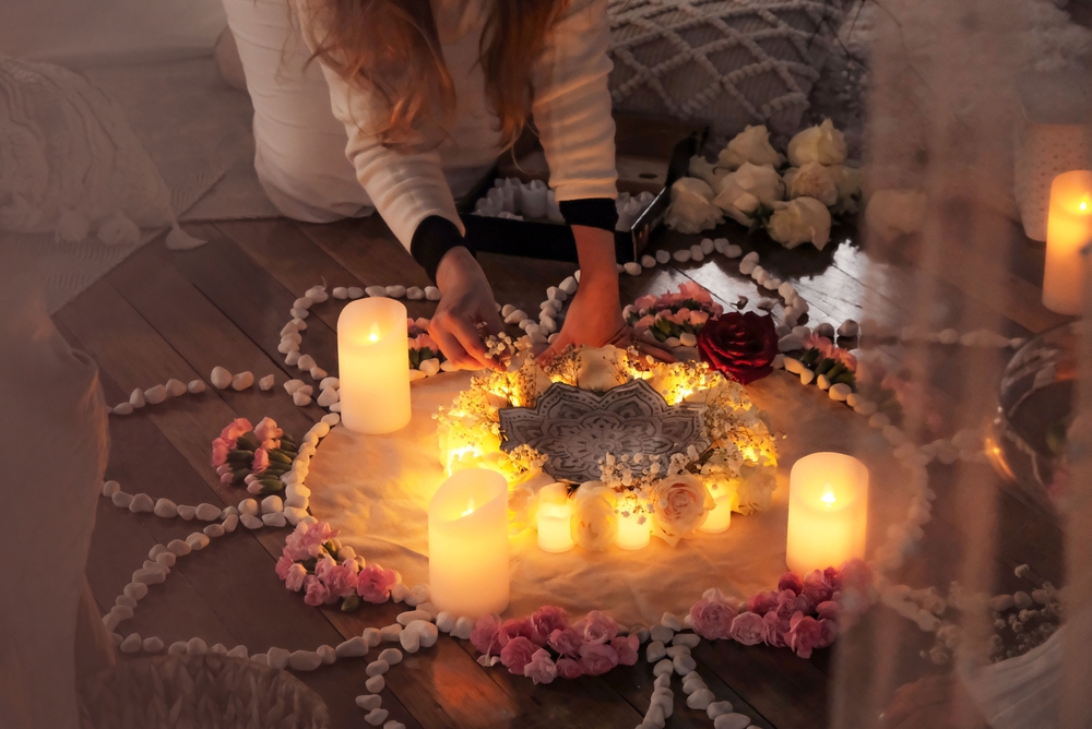 Beautiful women creating epowering flower mandala at women's circle event, flowers and candlelight