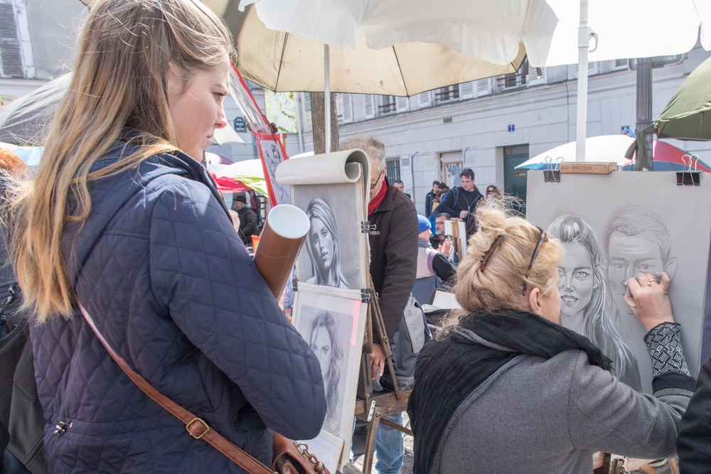 Artist painting and drawing portraits on sunny sunday day in Montmartre Place du Tertre famous artist retreat