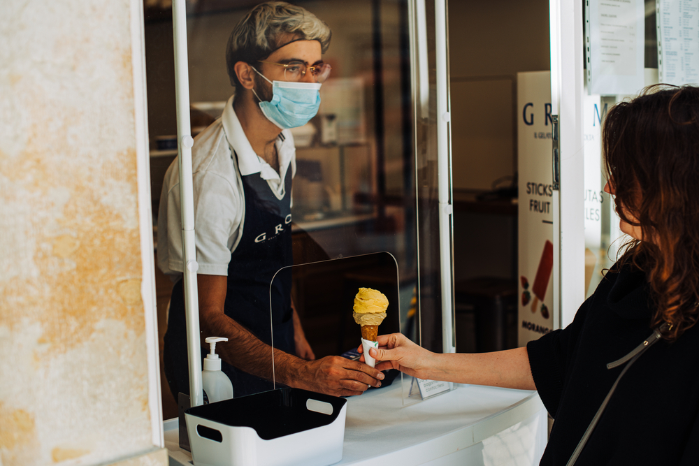 Woman buying ice cream in a small local store, Portuguese seller wearing protective mask to protect from coronavirus during Covid-19 pandemic in Portugal