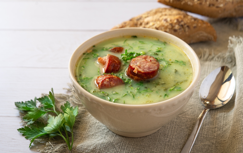 Portuguese style soup called Caldo Verde with traditional bread on white wooden Table. 