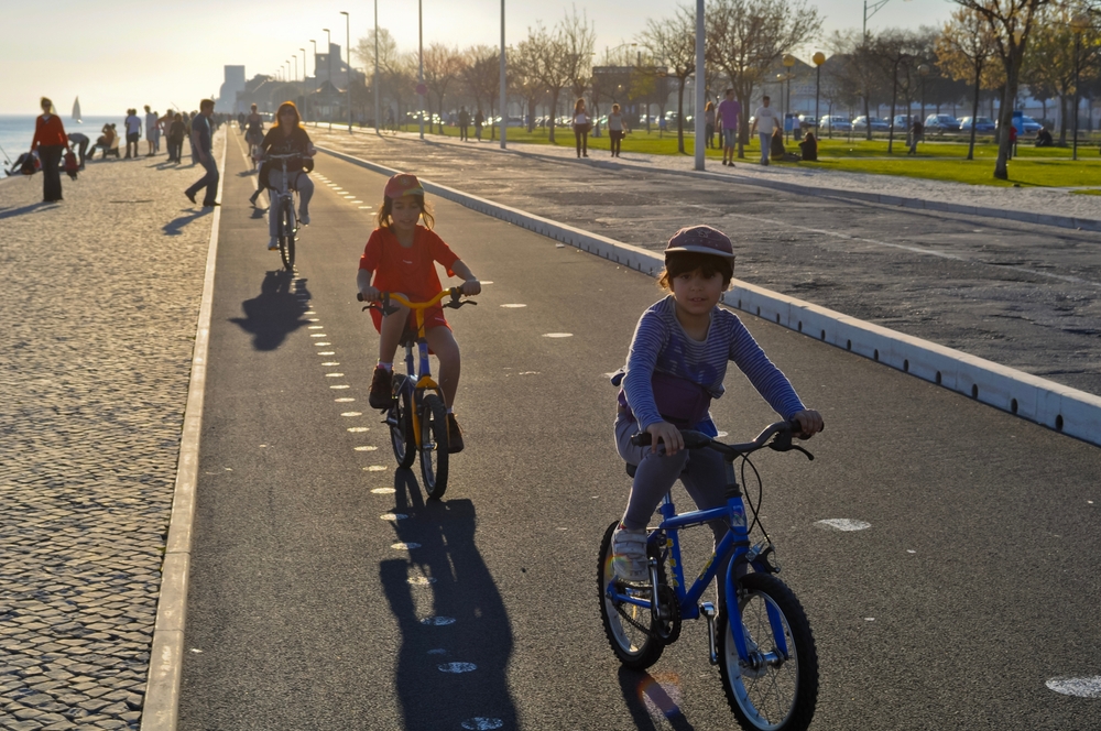  Children cycling by the river on a bike path in the late afternoon, active family