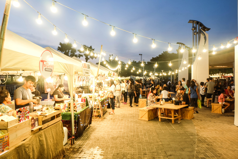 People and Tourist sitting,walking,eating and buying food at night street food market festival in a park. 
