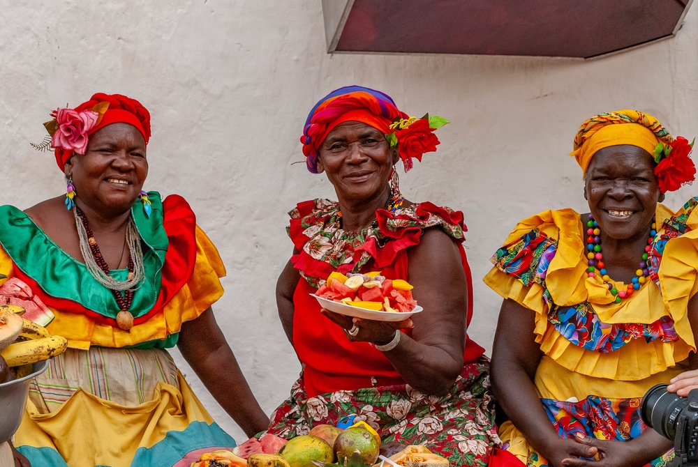 Cheerful fresh fruit street vendor aka Palenquera in the Old Town of Cartagena. Happy Afro-Colombian woman in traditional clothing, Colombian culture.