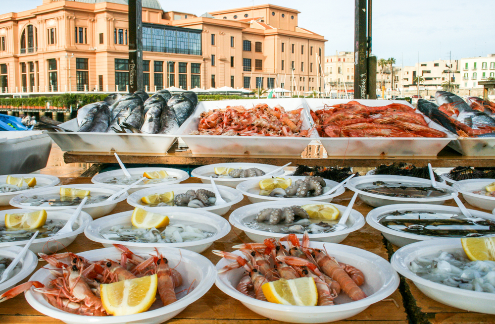 Open air street food fish market on Bari promenade with raw fresh sushi ready to eat, sea fruits: shrimp, oyster, sea urchin, cuttlefish, squid, octopus and salpa, sole and various fish