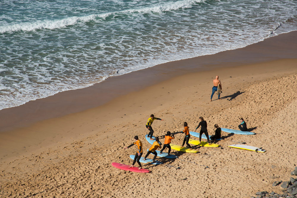 Beach landscape with active and sporty vacationers, such as bathers, swimmers and surfers.