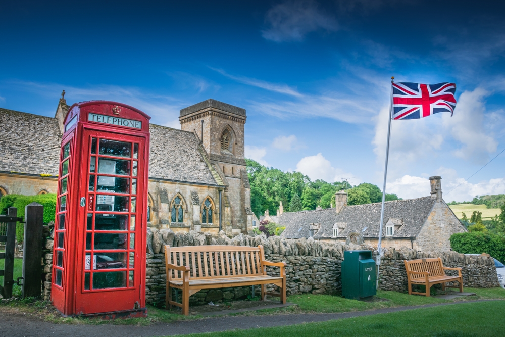 A classic British village with church, red telephone booth and Union Jack