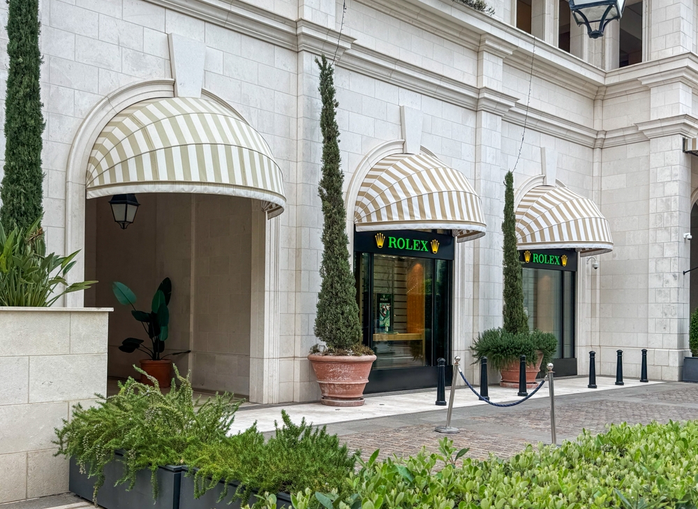 Rolex store framed by arched entrances and greenery showcases watches in the luxury shopping arcade of the REGENT Hotel