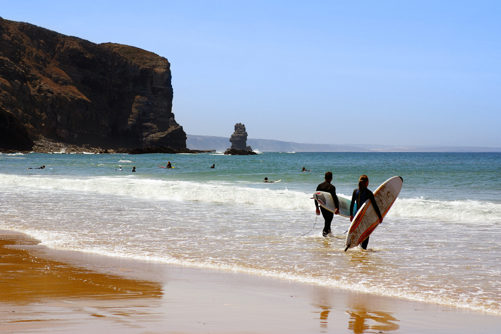 Two surfers ready to enter the sea in Arrifana Beach, Algarve Portugal