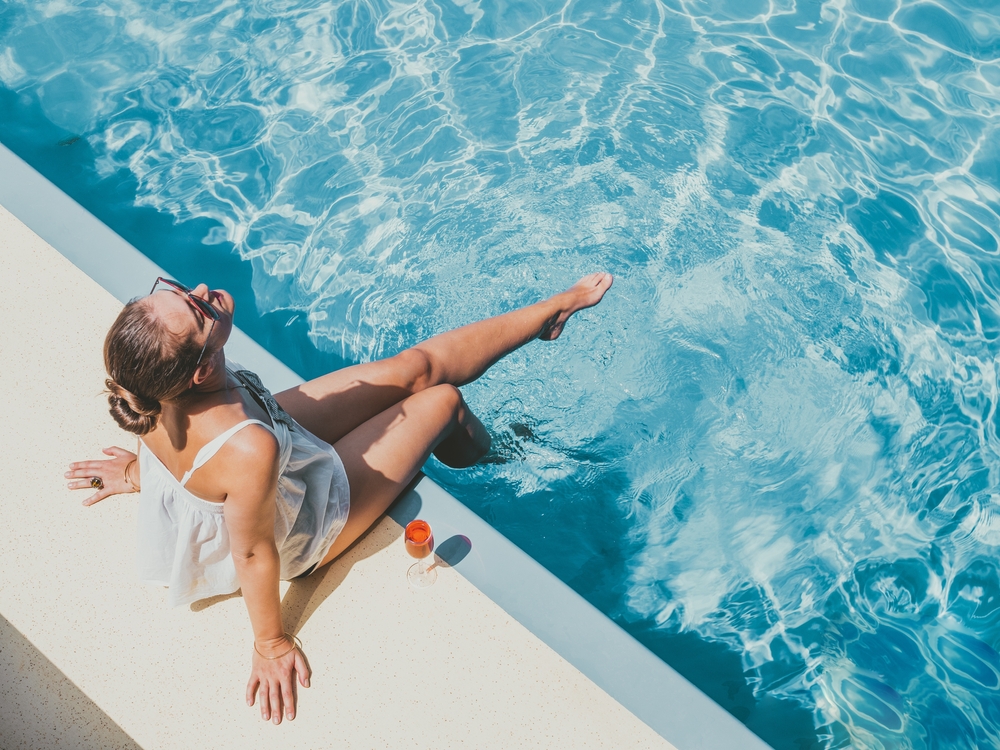 Fashionable woman sitting by the pool on the empty deck of a cruise liner.