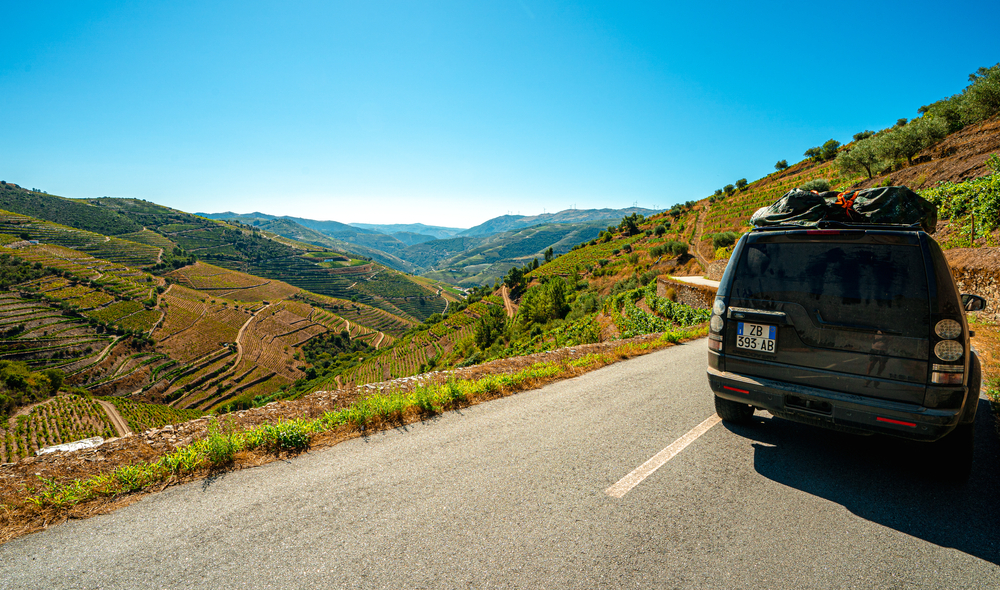 Lifestyle photo of a black Land Rover Discovery 4 driving along scenic Portuguese coastline.