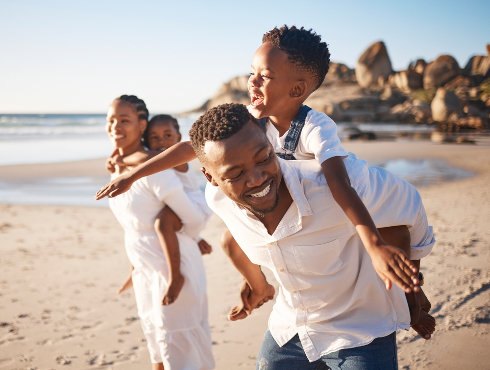 Piggyback, playing and black family at beach for fun on tropical vacation, travel or getaway.