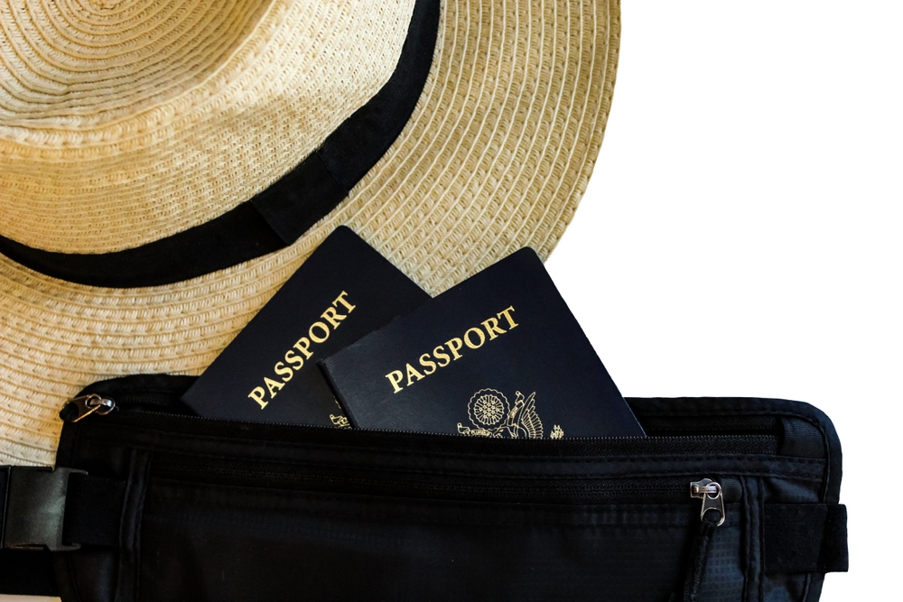 macro close-up of straw woven fedora hat travel accessory with passport and wallet money belt isolated on white table.