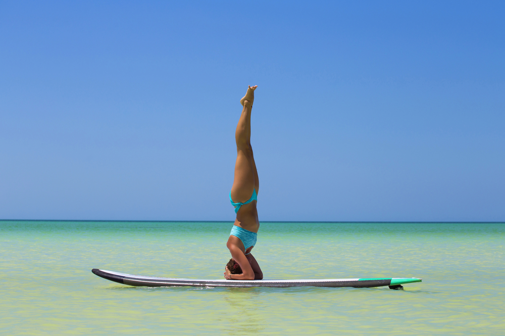 Woman practicing SUP yoga, on a paddleboard in the Caribbean