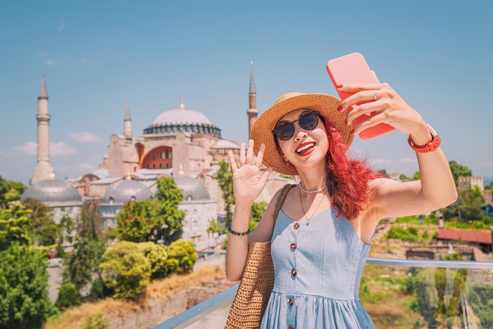 A Turkish woman takes a selfie in front of the Hagia Sophia, capturing the historic landmark during her summer vacation in Istanbul