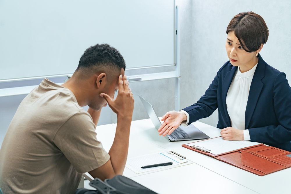 A Japanese female staff member interviewing a troubled black man