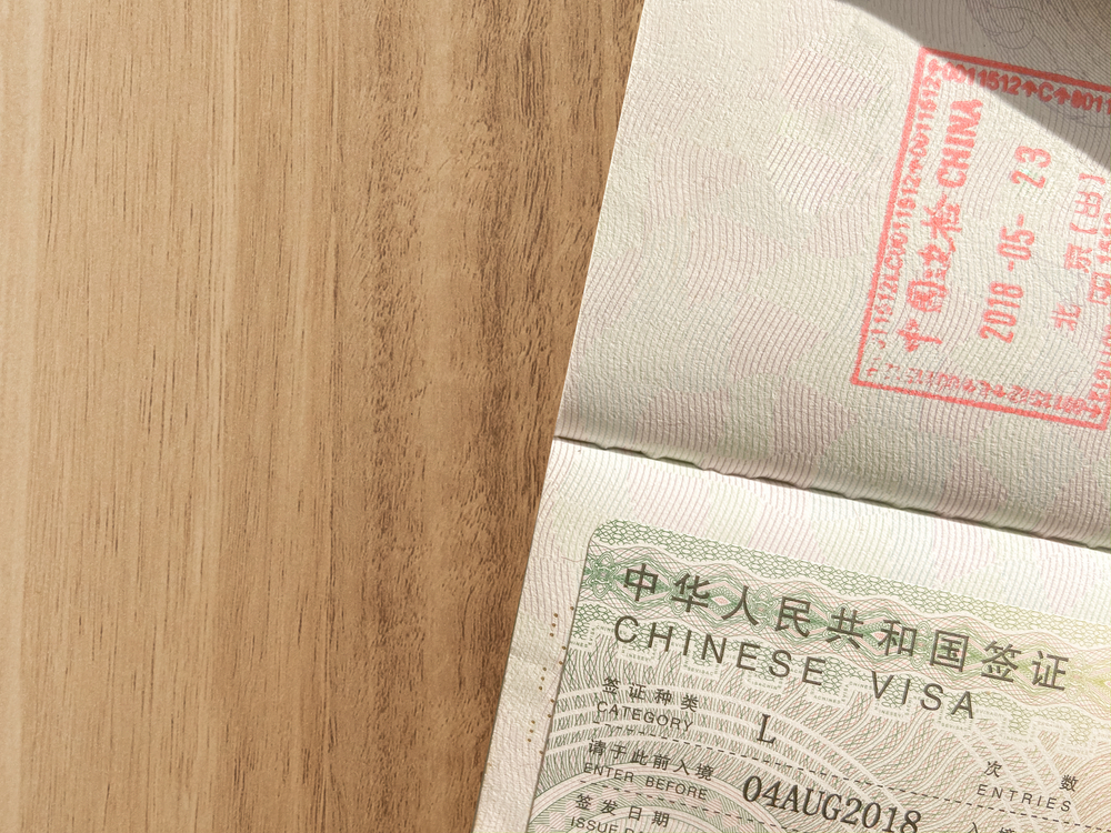 Chinese visa for travel on wooden brown table. Close Up Chinese visa is approved, applied and added to the passport for traveling to China