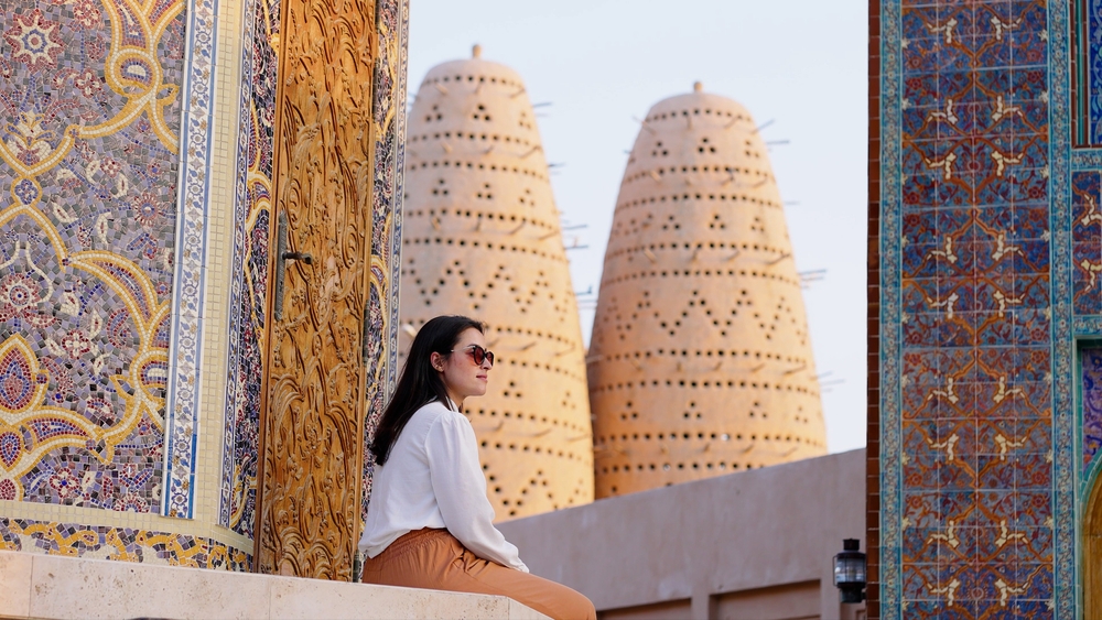 tourist woman sitted at Blue mosque of Katara village made of colorful mosaic in Doha Qatar showing Pigeon tower behind