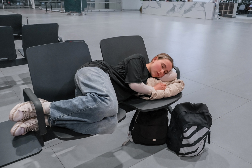 Travel, airport, woman waiting for a flight sleeps on a seat at the airport, solo travel, airport transit area, travel experiences, authentic travel