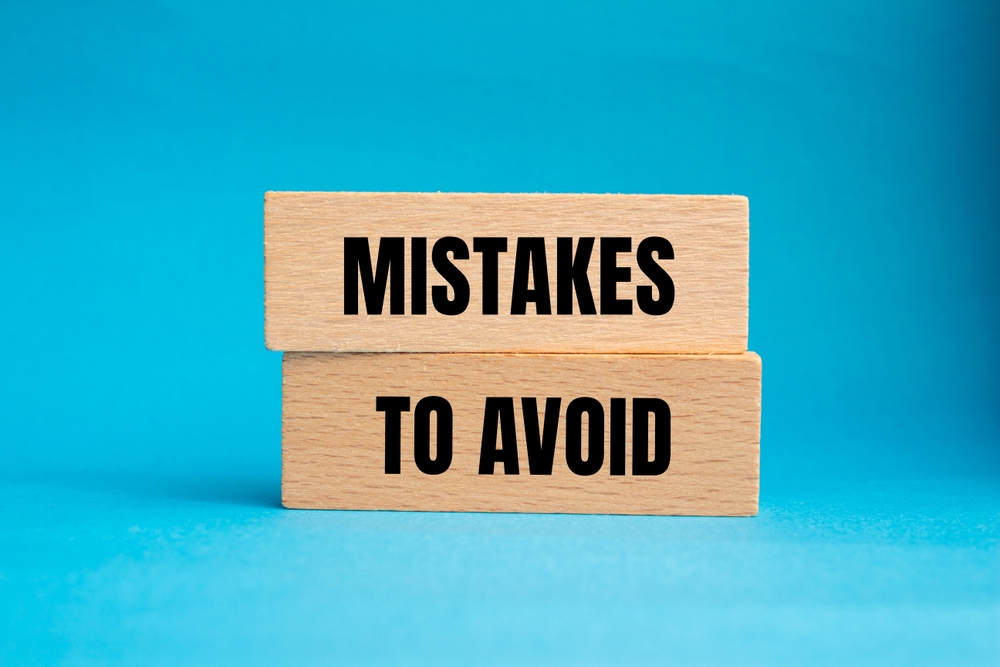 Mistakes to avoid message written on wooden blocks with blue background. 
