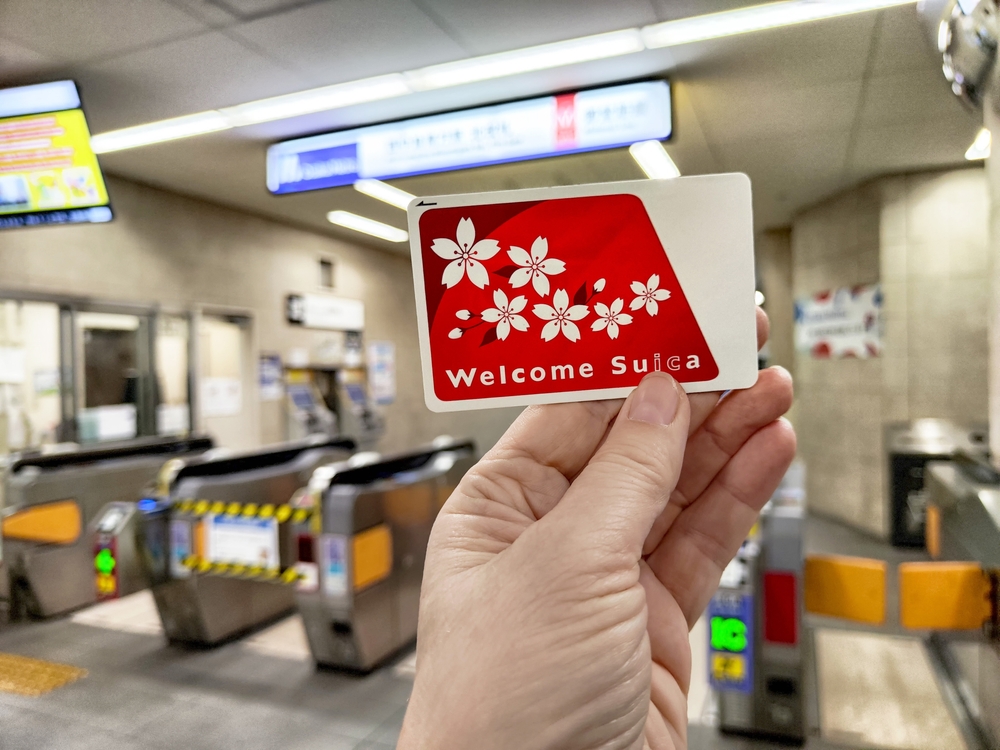 Tourist holds a welcome Suica transport card in a bustling subway station in Japan, ready for easy access to public transit.